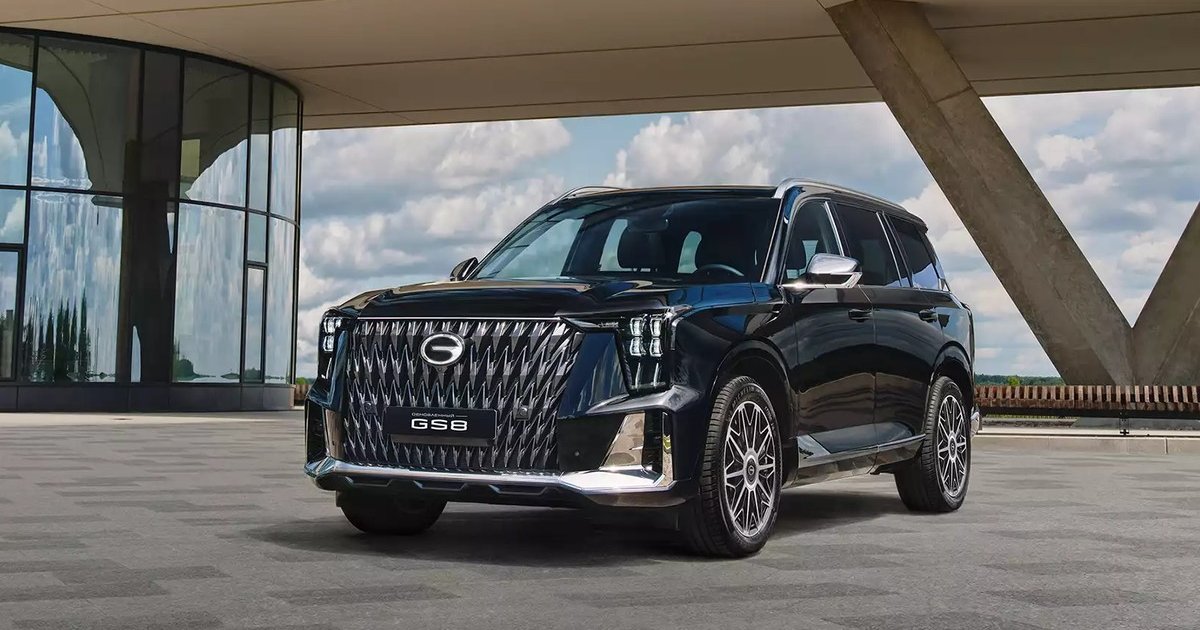 Тёмно-синий трёхрядный кроссовер GAC GS8 на площадке у современного здания